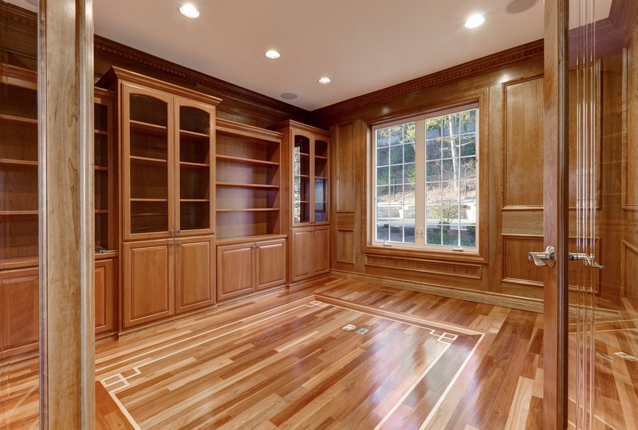 Custom-built bookcase unit in a spacious modern design, featuring full-wall wooden shelves in a light natural color.  