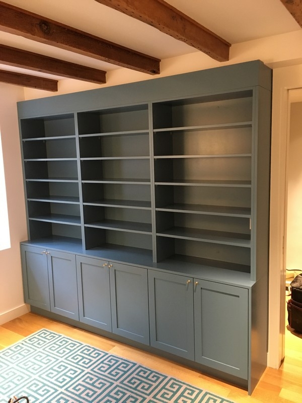 Elegant, full-wall custom bookcase with large, dark color shelves, designed to add a modern and spacious feel to any room.  