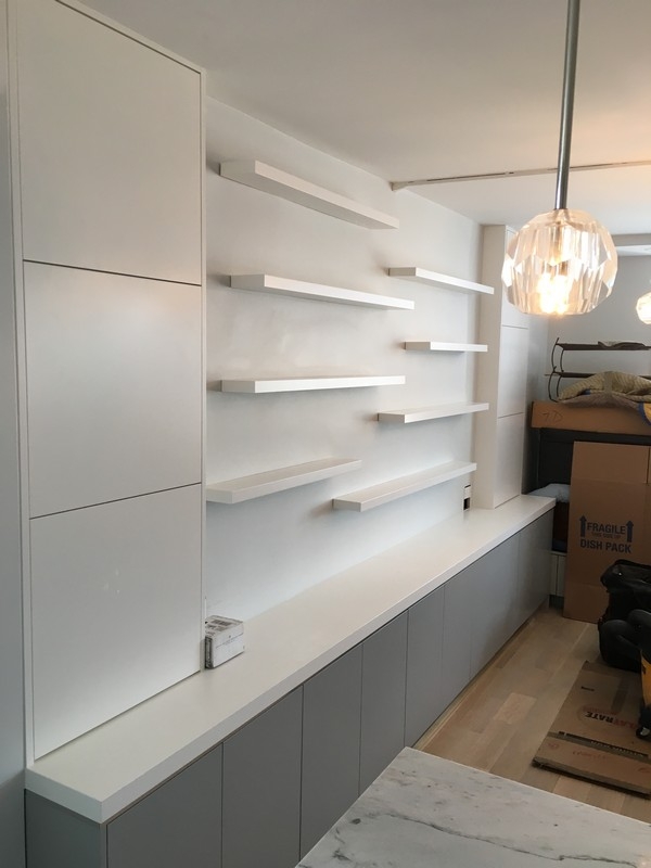 Custom, built-in bookcase unit with big, spacious shelves in a white wood color, adding warmth to modern interiors.  