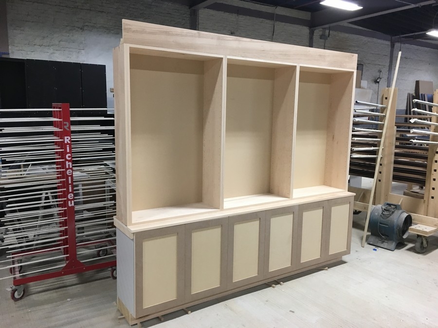 Spacious, custom bookcase unit in a light natural wood color, featuring big, built-in shelves for a modern home library.  