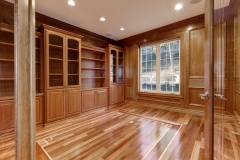 Custom-built bookcase unit in a spacious modern design, featuring full-wall wooden shelves in a light natural color.  