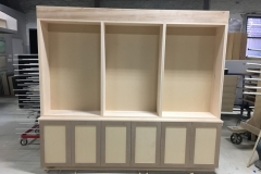 Custom, built-in bookcase unit with spacious wooden shelves in a light color, blending seamlessly with modern interiors.  