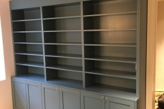 Elegant, full-wall custom bookcase with large, dark color shelves, designed to add a modern and spacious feel to any room.  