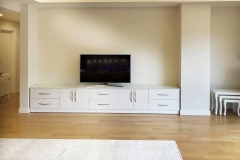Modern, custom-made bookcase TV unit with a full wall of white wooden shelves, designed for spacious and stylish storage.  