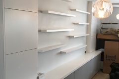 Custom, built-in bookcase unit with big, spacious shelves in a white wood color, adding warmth to modern interiors.  