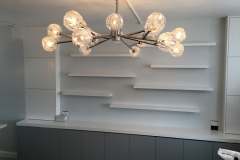 Sleek, full-wall custom bookcase with spacious shelves in a clean white color, perfect for modern interiors.  