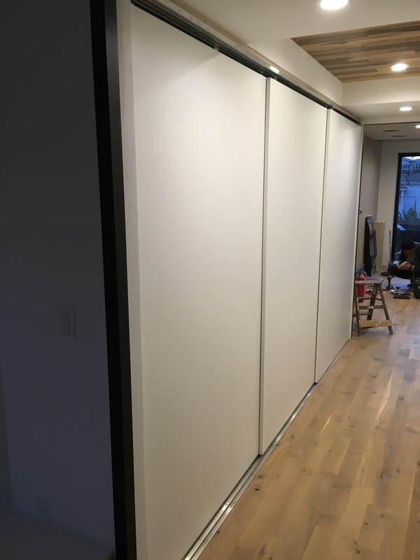 Custom, modern wardrobe with large, built-in cabinets in a light hazelnut color.             