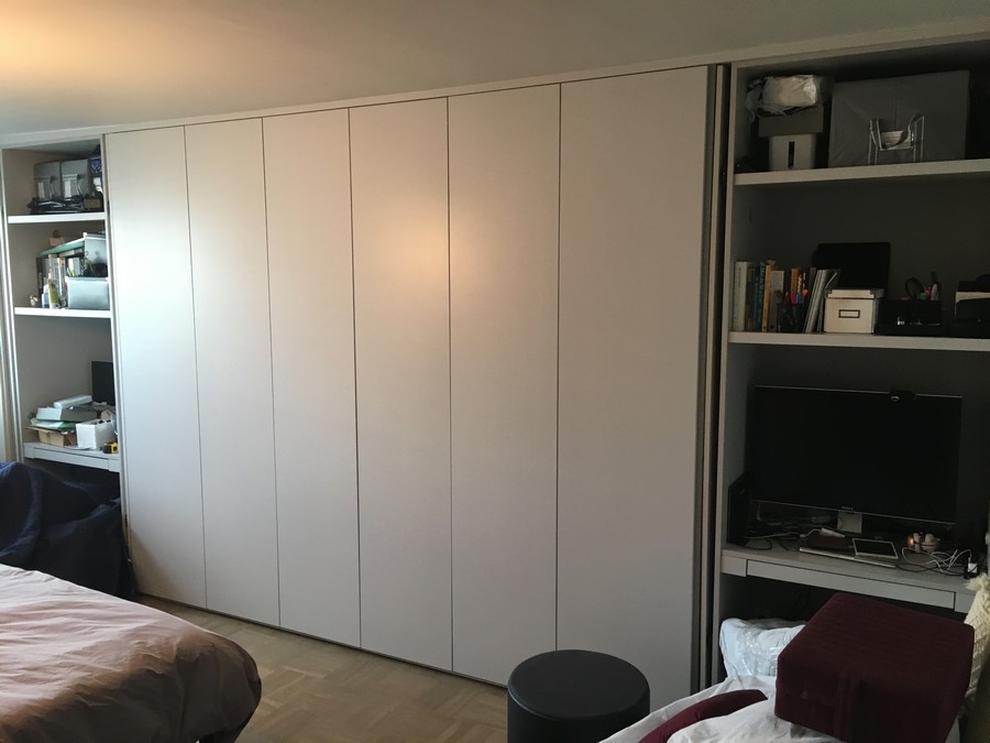 Custom, spacious wardrobe with built-in cabinets in a modern, light wood color.            