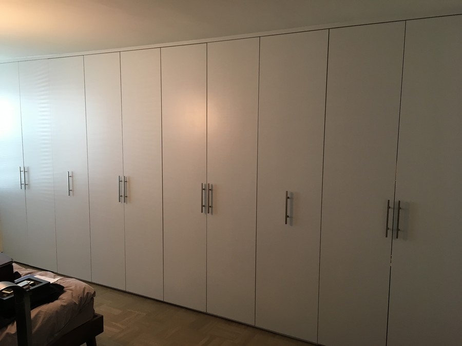 Elegant, full wall wardrobe custom-made with big cabinets in a hazelnut color.             