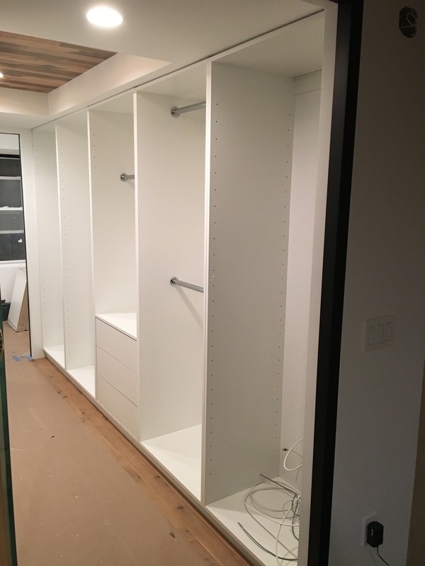 Custom-built, full wall wardrobe with large cabinets in a modern, light color.            
