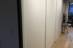 Custom, modern wardrobe with large, built-in cabinets in a light hazelnut color.             