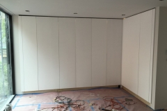 Spacious, custom wardrobe with full wall, natural wood cabinets and a sleek design.            