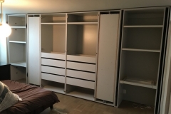 Custom, modern wardrobe with big, built-in cabinets in a light, natural wood color.             