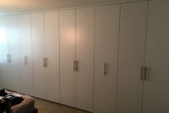 Elegant, full wall wardrobe custom-made with big cabinets in a hazelnut color.             