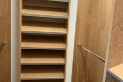 Modern, custom-made wardrobe with full wall, white cabinets and a spacious layout.             
