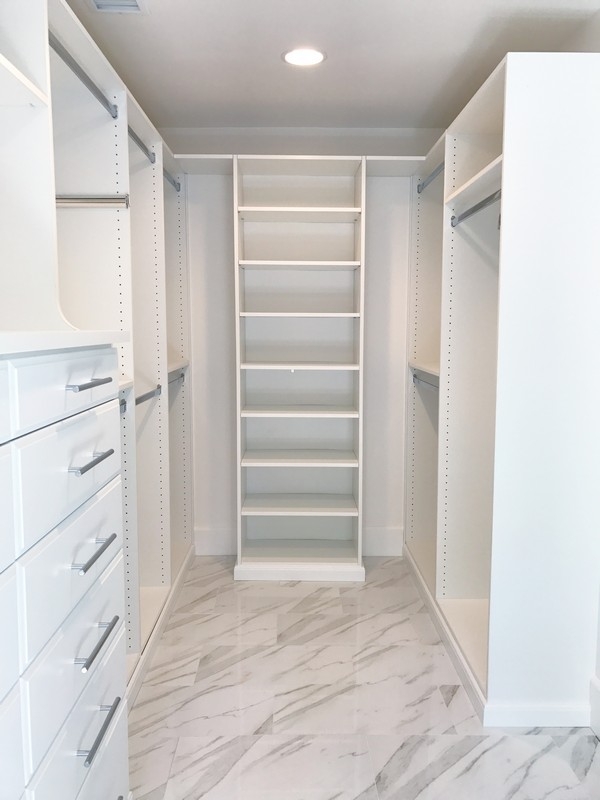 Spacious, modern walk-in closet custom-made with full-wall, darker-colored wooden shelves for a sleek look.  