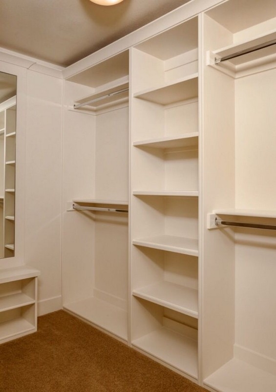 Custom-built, big walk-in closet with wooden shelves in a natural color, designed for ample storage and organization.  