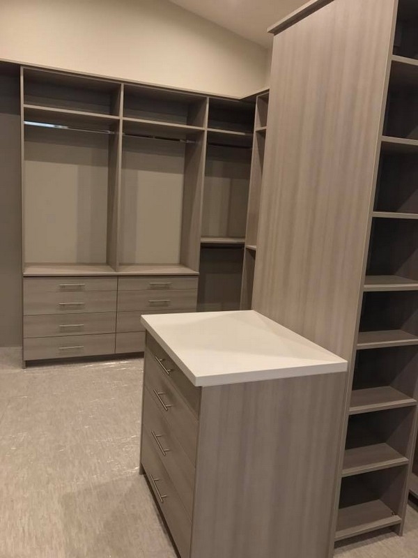 Large, custom walk-in closet featuring full-wall, built-in wooden units in a crisp white color for a modern interior.  