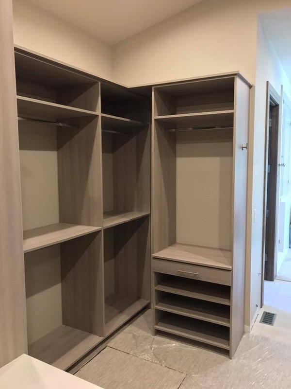 Elegant custom-made closet with spacious, light-colored wooden shelving, offering a full-room organization solution.  