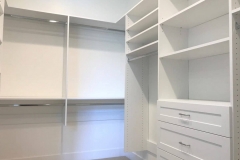 Big, custom-made walk-in closet with built-in wooden storage in a rich, darker color, providing elegant organization options.  