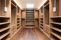 Elegant custom walk-in closet with built-in wooden cabinetry in a warm hazelnut color, offering expansive storage solutions.  
