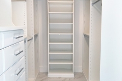 Spacious, modern walk-in closet custom-made with full-wall, darker-colored wooden shelves for a sleek look.  