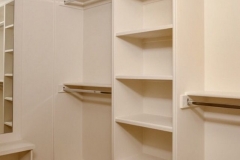 Custom-built, big walk-in closet with wooden shelves in a natural color, designed for ample storage and organization.  