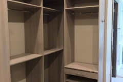 Elegant custom-made closet with spacious, light-colored wooden shelving, offering a full-room organization solution.  