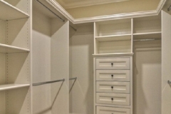 Modern, custom closet design with big, hazelnut-colored wooden shelves, creating a warm and inviting walk-in space.  