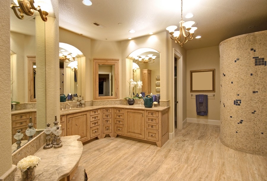 A large bathroom in light wood colors with a big L-shaped custom vanity