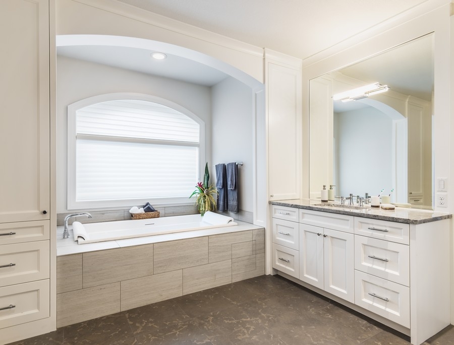 A bathroom in white color with a big mirror and a custom vanity