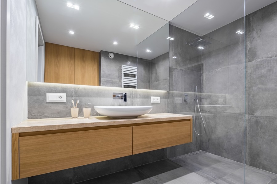 a large bathroom in grey marble with a brown custom vanity