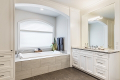 A bathroom in white color with a big mirror and a custom vanity