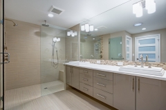 light brown bathroom with a glass door shower and a large custom vanity with a big mirror