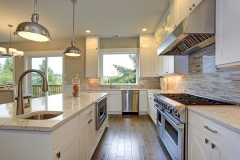 Airy, custom kitchen with large white cabinets and a sleek, contemporary wood finish.