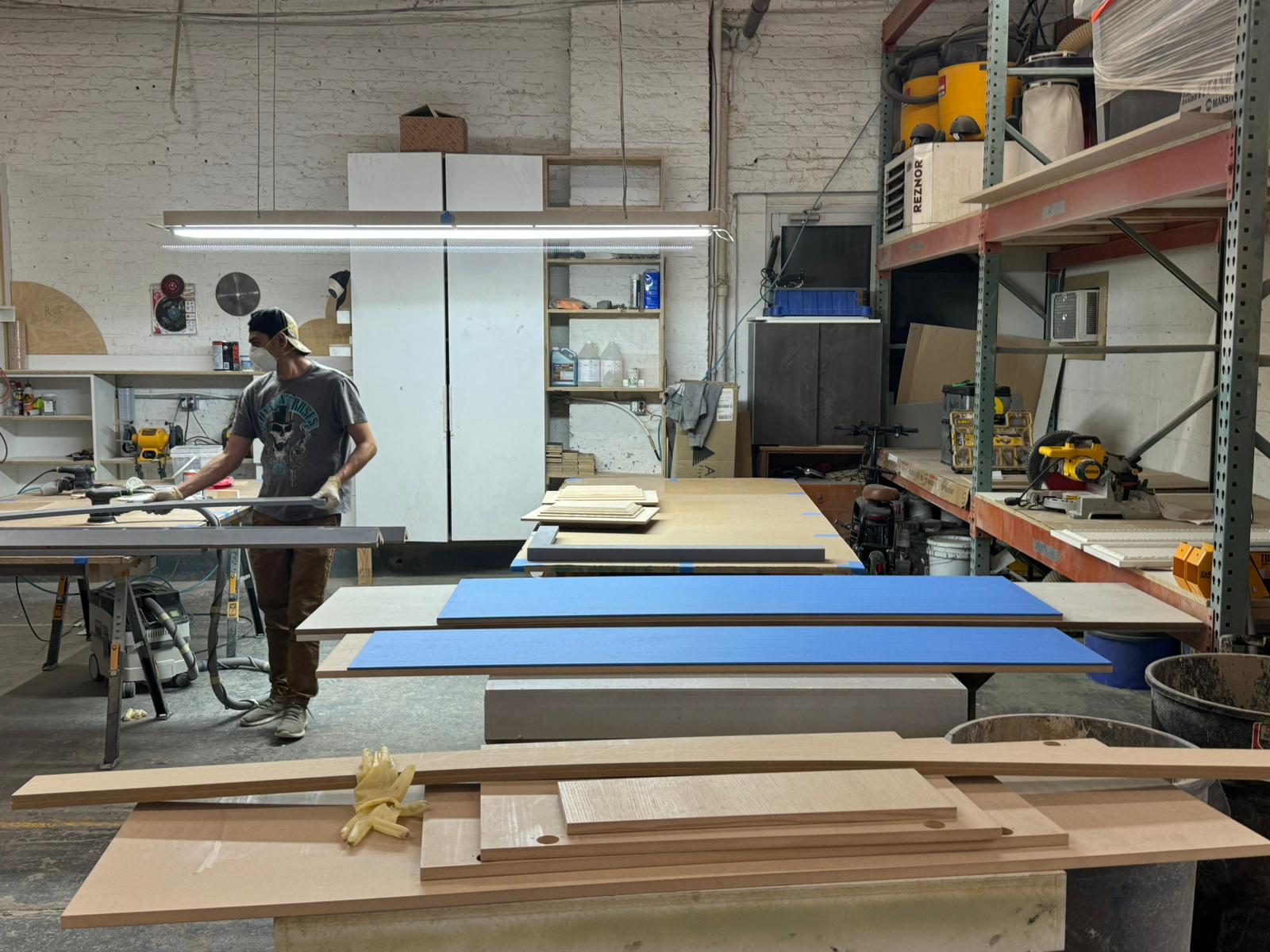 A woodworker wearing uniform and mask is at work in our millwork shop in Brooklyn